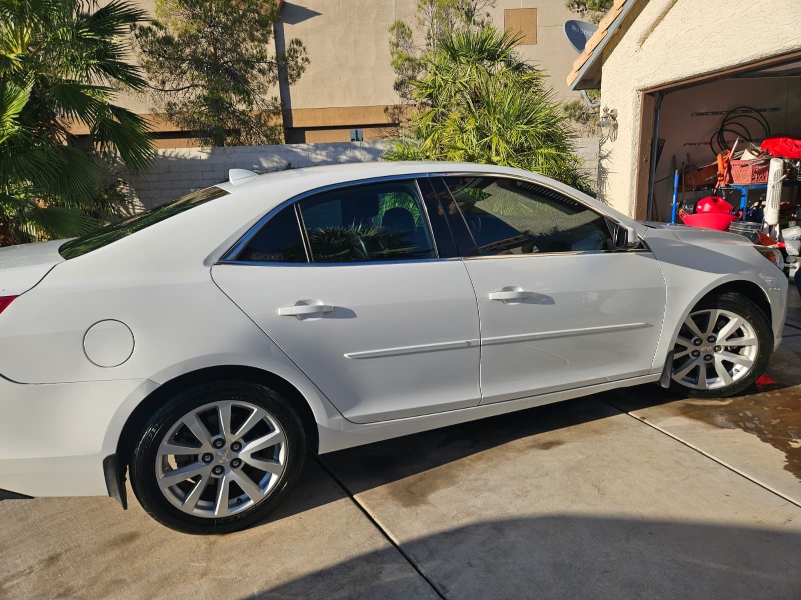 White sedan parked in a driveway, rear three-quarter view